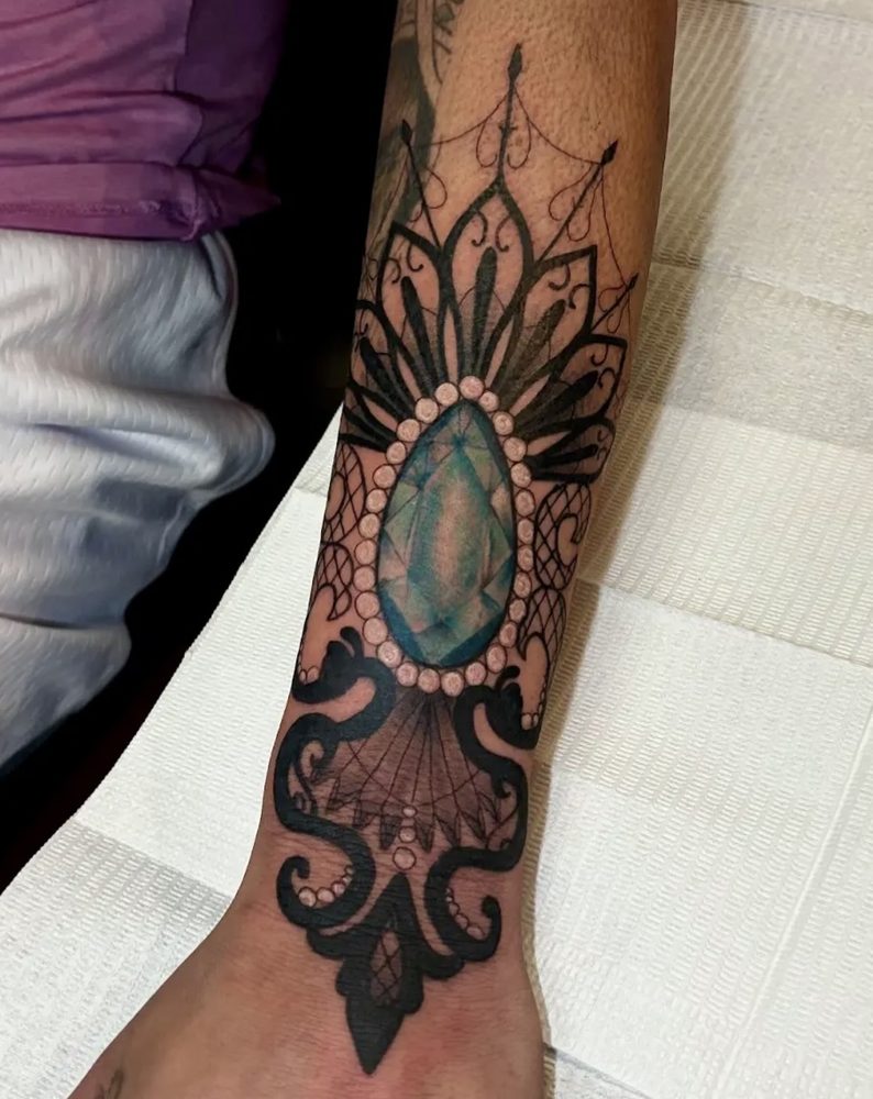 Black-and-grey ornamental lacework framing a teal gemstone