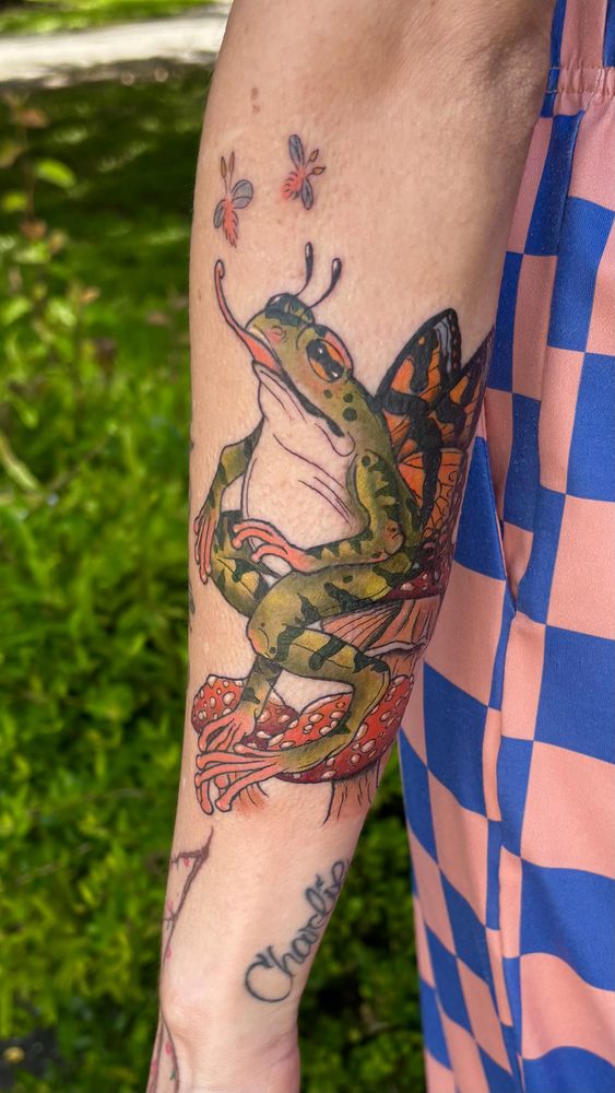 Neo-traditional frog with monarch butterfly wings perched on red spotted mushrooms